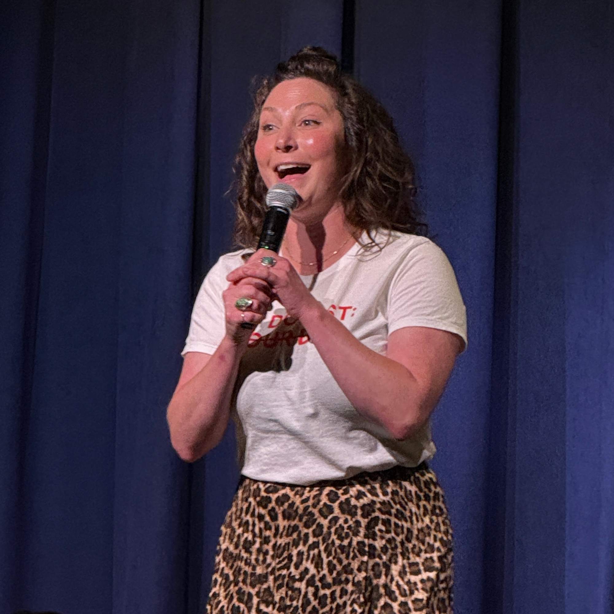 Comedian laughing into the microphone at the Snowmass Live Comedy Series, The Collective Snowmass