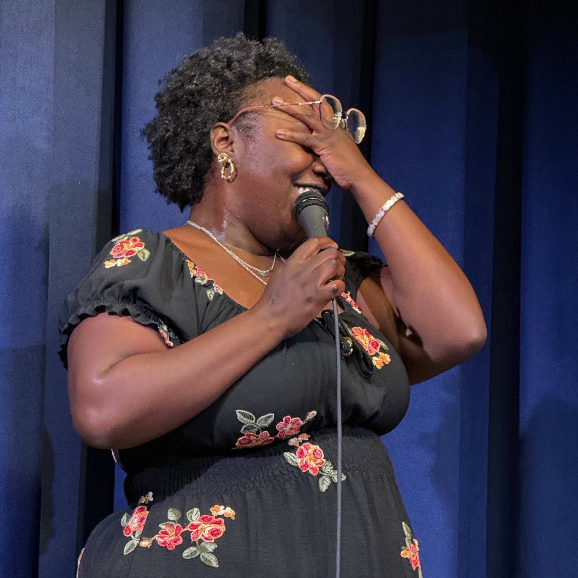 Comedian cracking up with a hand over her face at the Snowmass Live Comedy Series, The Collective Snowmass