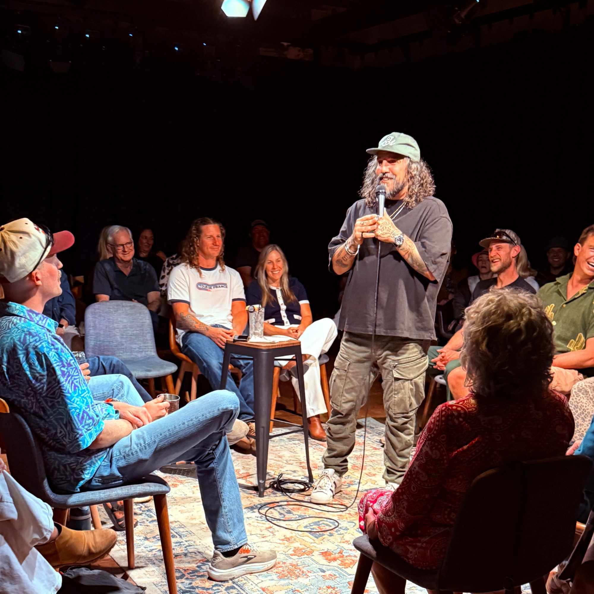 Comedian performing in the round to a packed room at the Snowmass Live Comedy Series, The Collective Snowmass