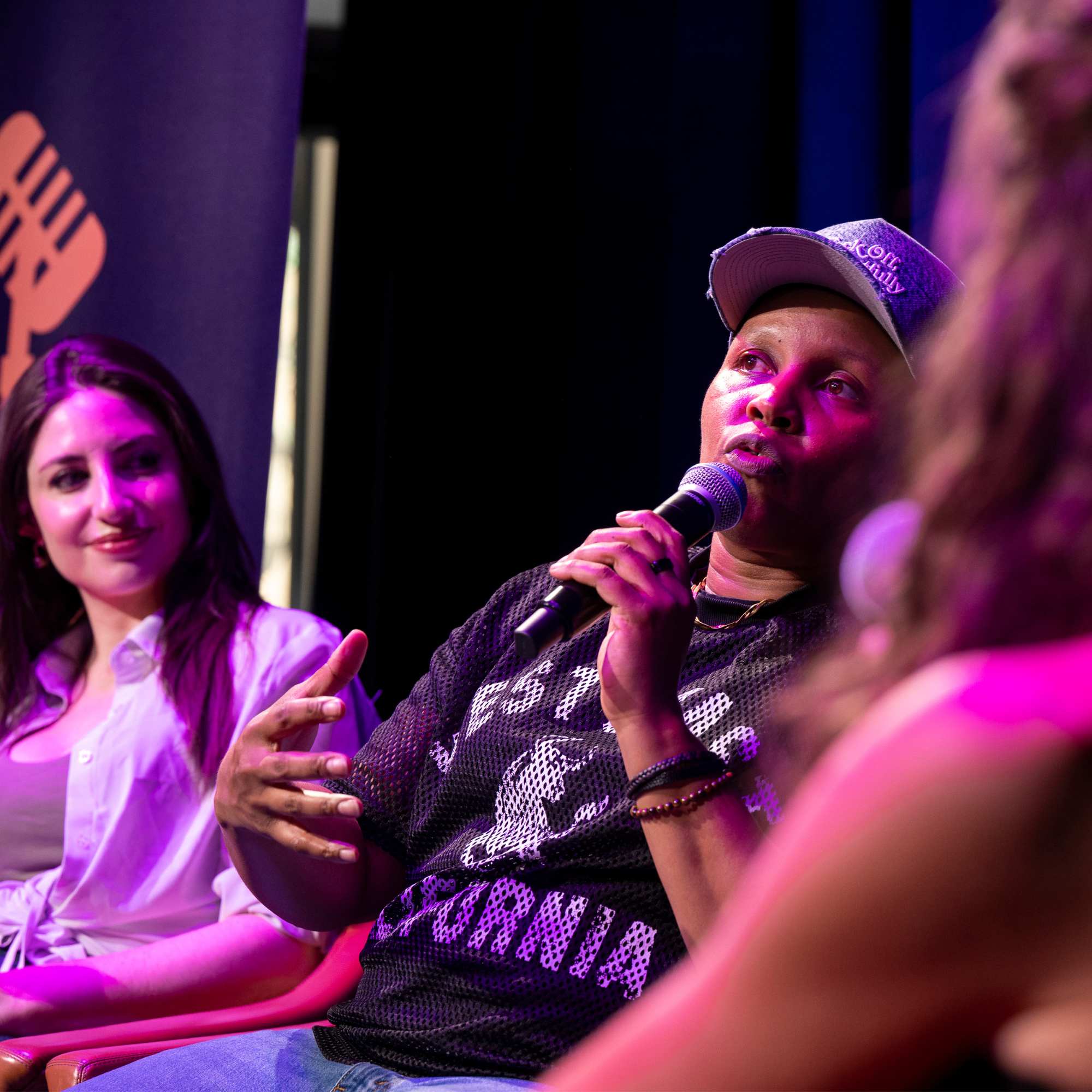 Comedian on a panel under purple stage lights at Snowmass Live Comedy WKND!, The Collective Snowmass