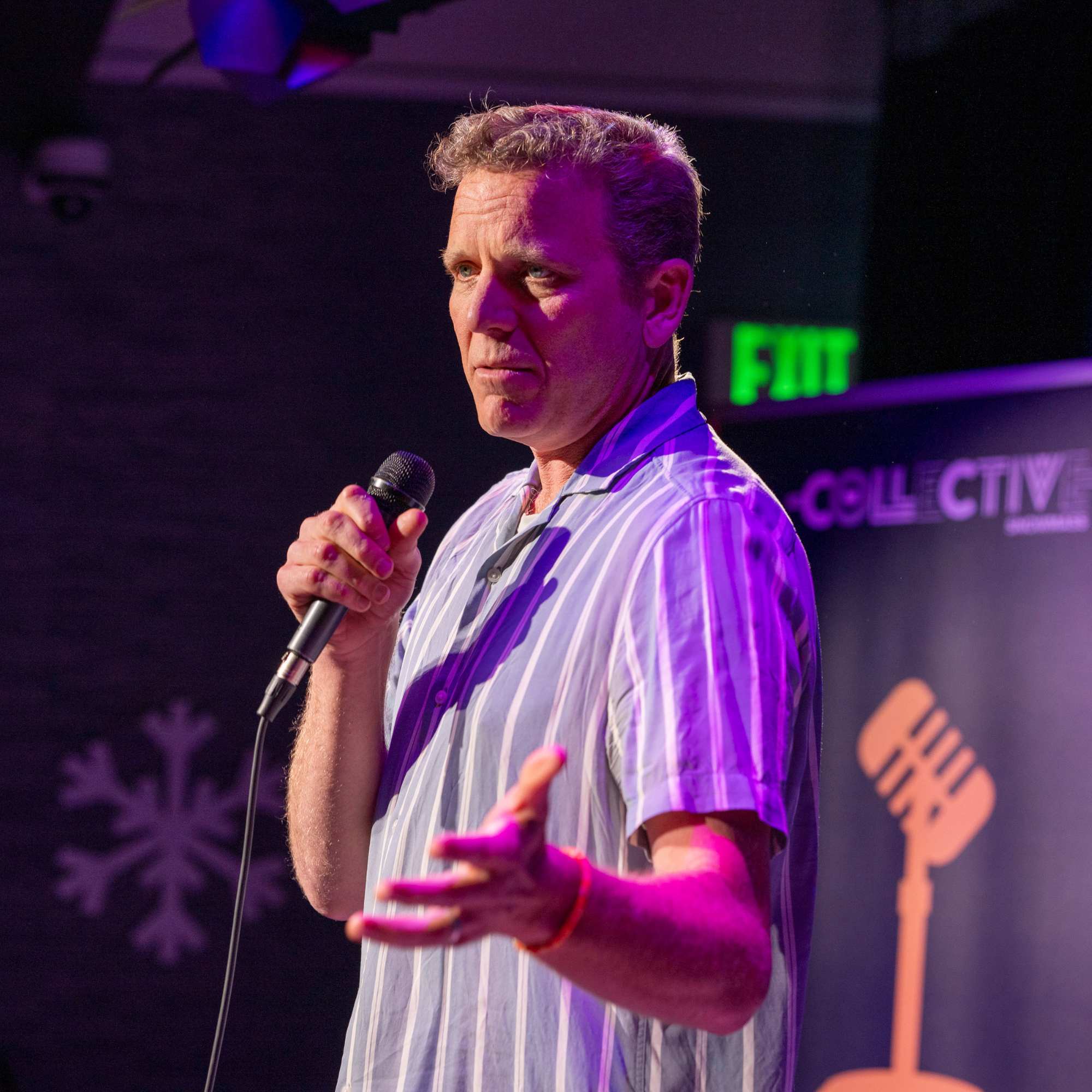 Comedian gesturing on stage beside The Collective sign at Snowmass Live Comedy WKND!, The Collective Snowmass