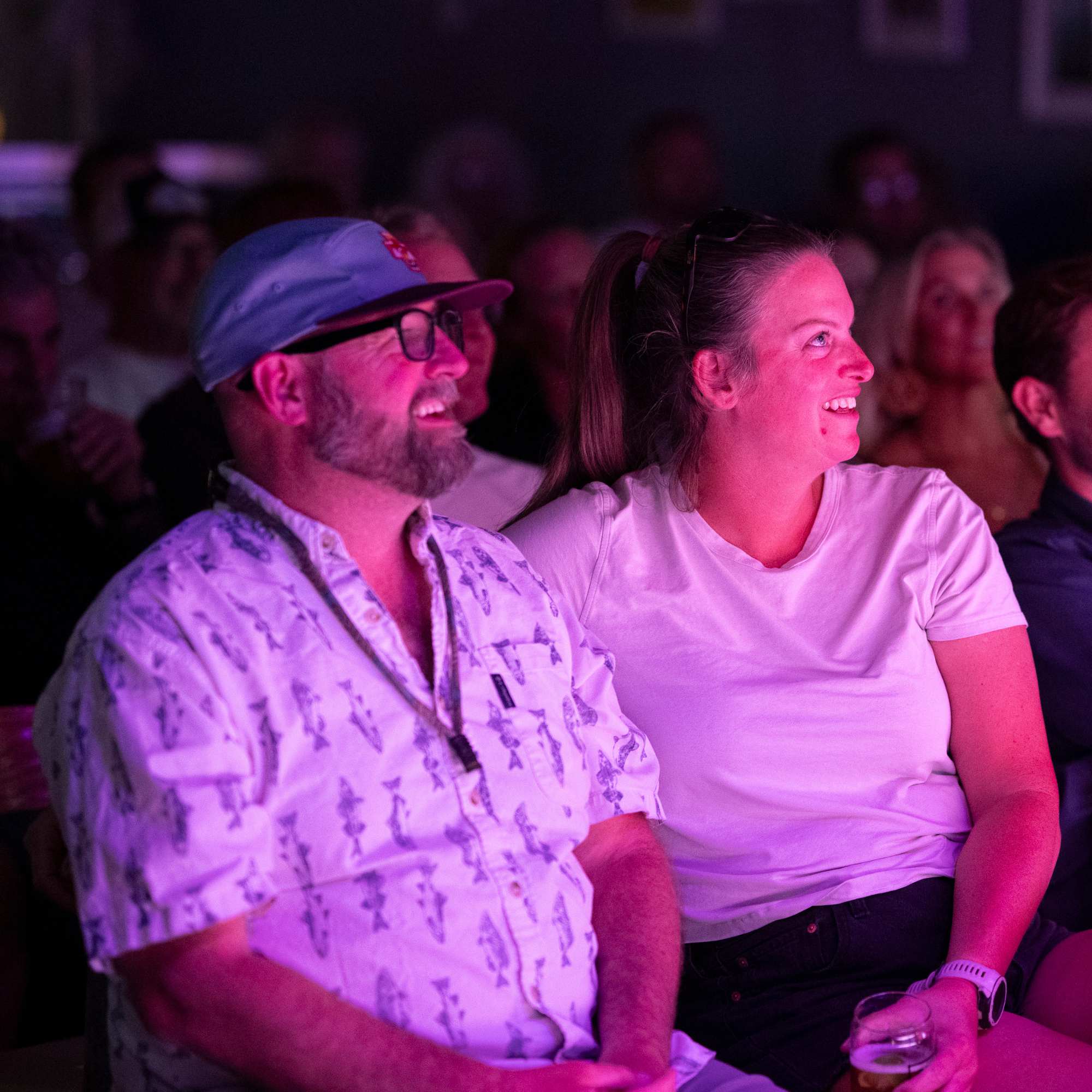 Audience members laughing under pink stage lights at Snowmass Live Comedy WKND!, The Collective Snowmass