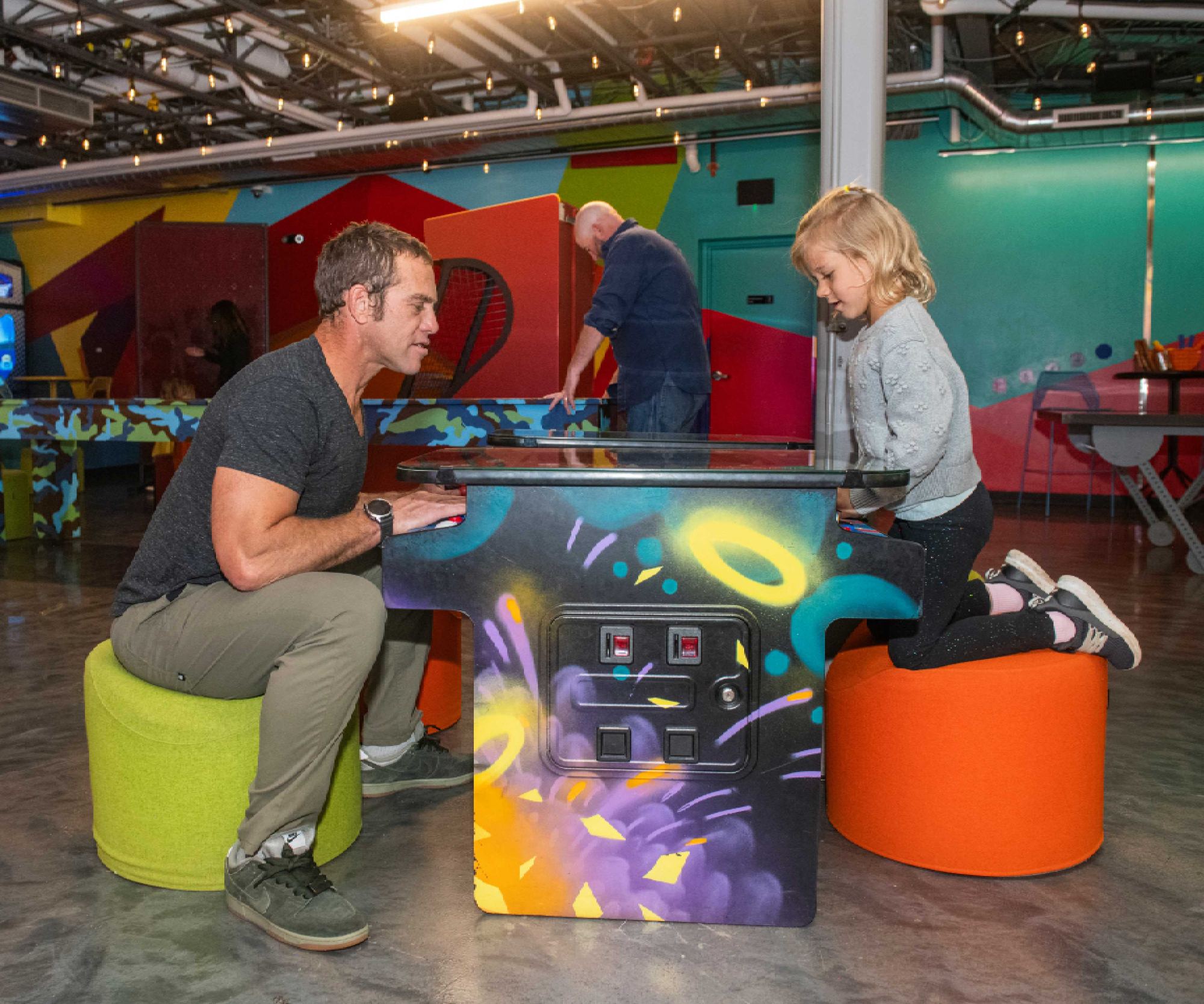 Dad and daughter playing an arcade game in the Game Lounge, The Collective Snowmass
