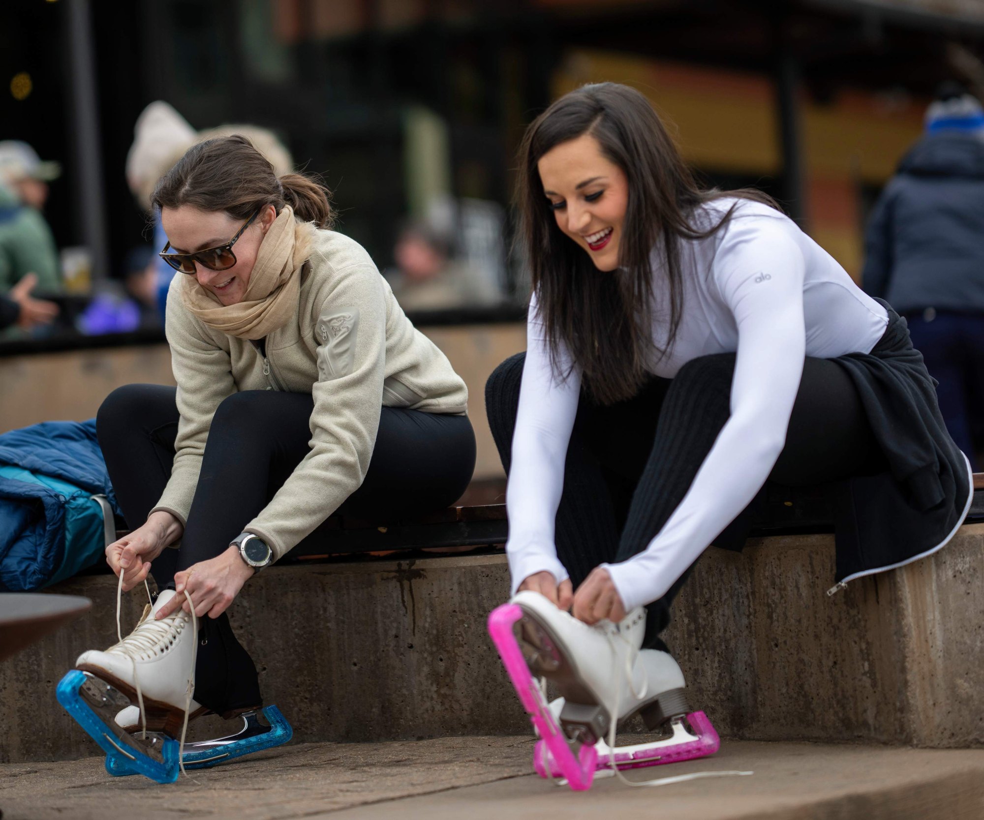 Two friends lacing up skates at The Rink, The Collective Snowmass