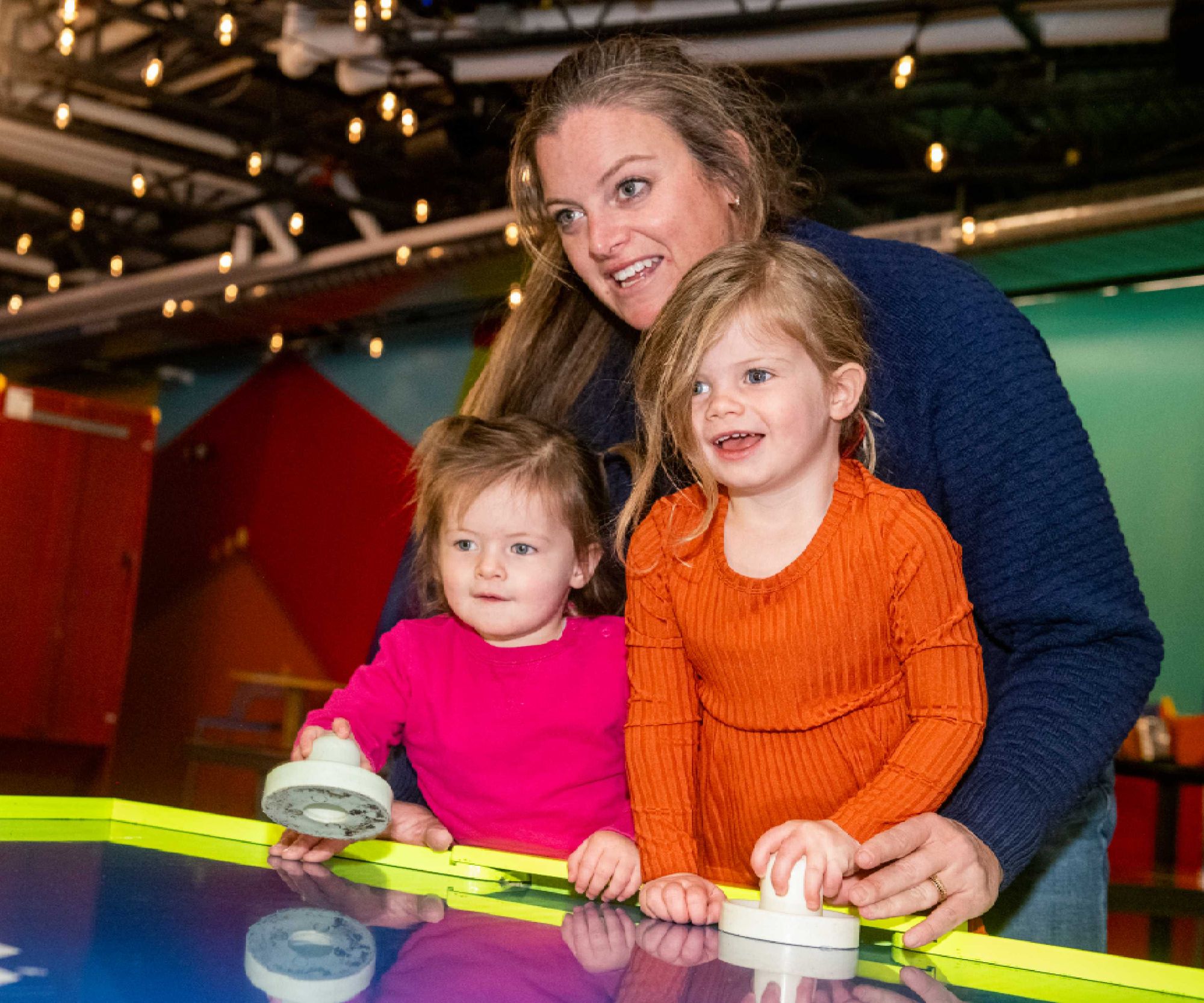 Mom and kids playing air hockey in the Game Lounge, The Collective Snowmass